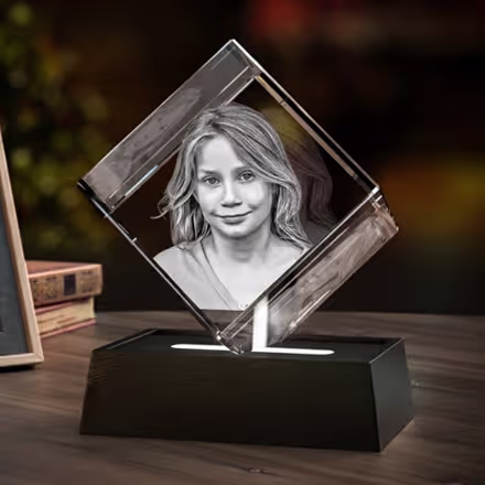 3D Photo Crystal Diamond engraved with a smiling young girl, displayed on a black LED light base beside the original photo.