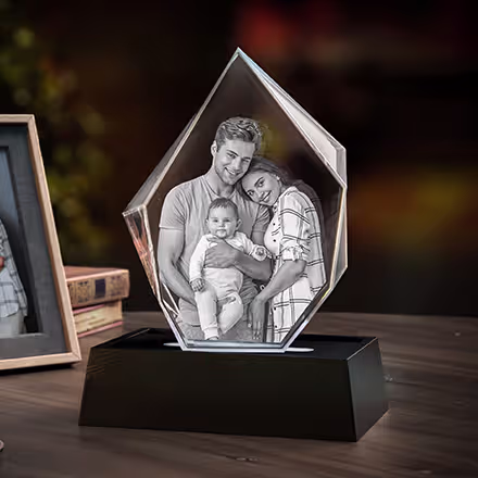 3D Photo Crystal Iceberg engraved with parents and their baby, displayed on a black LED light base beside the original family photo.